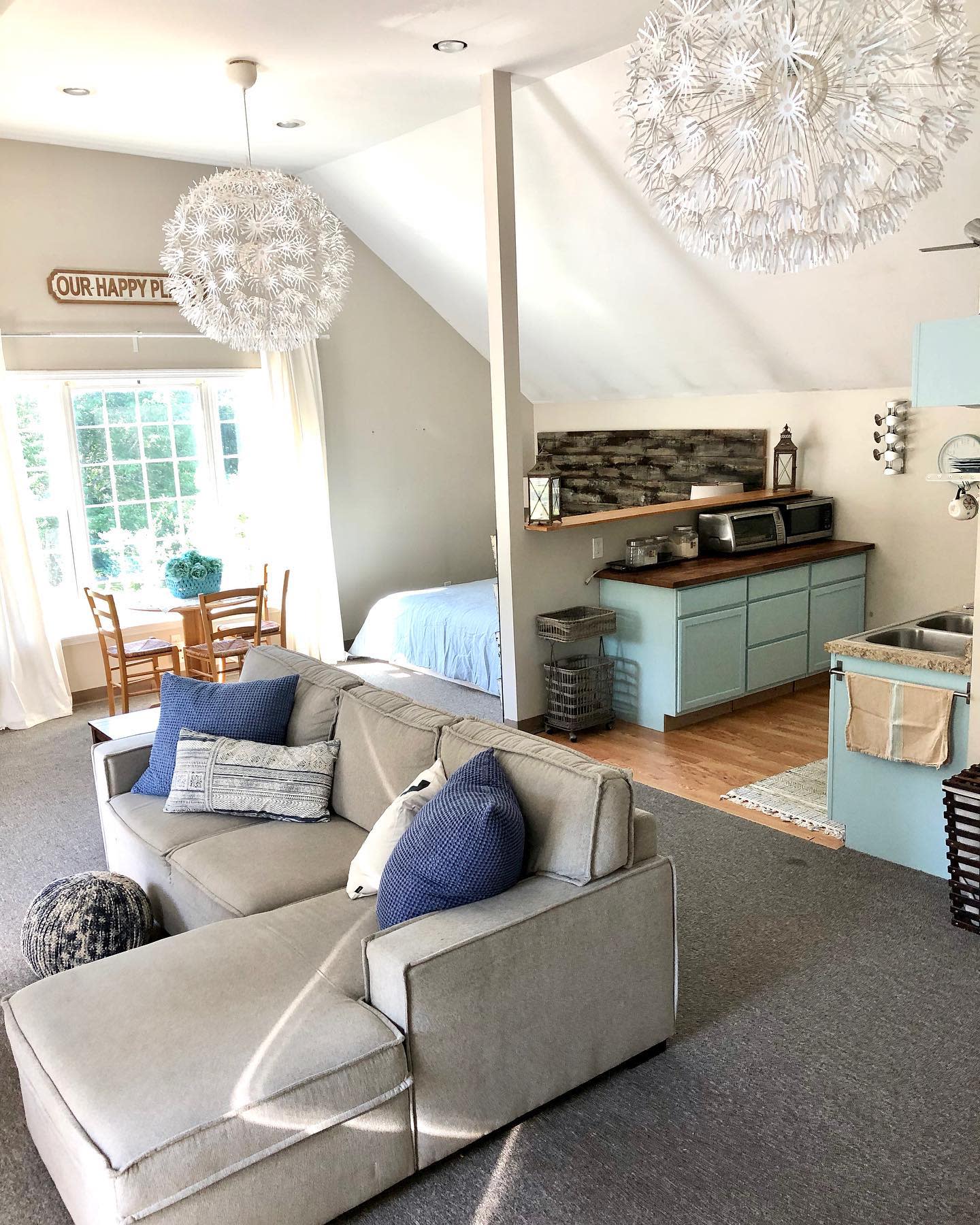 open plan apartment gray sofa blue kitchen bedroom table and chairs 